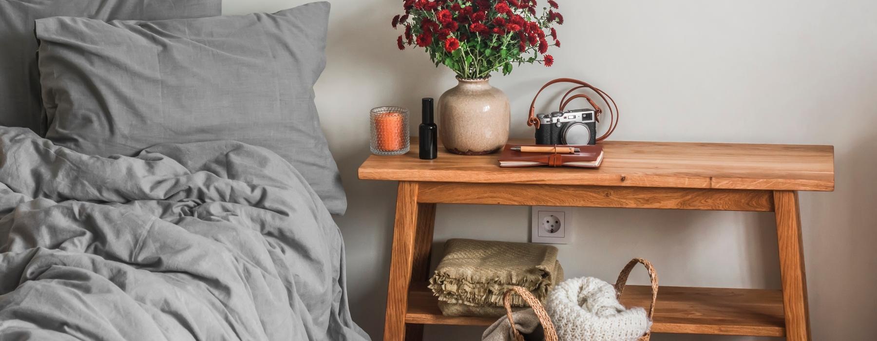 a basket of flowers on a table next to a bed
